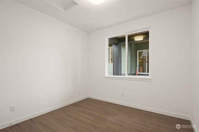 spare room with baseboards and dark wood-style floors