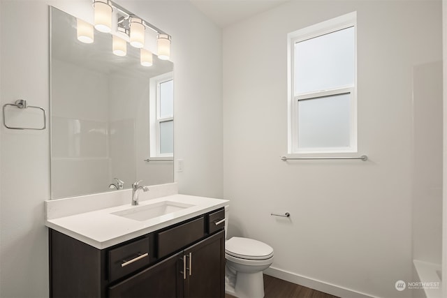 bathroom featuring baseboards, toilet, wood finished floors, and vanity