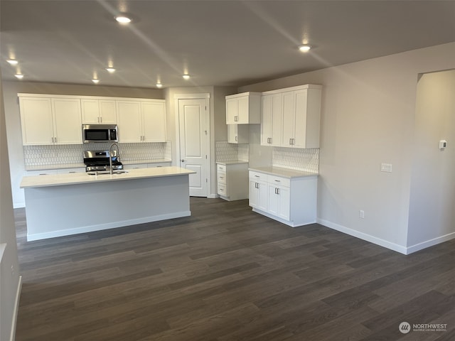 kitchen with white cabinets, sink, dark hardwood / wood-style floors, an island with sink, and stainless steel appliances