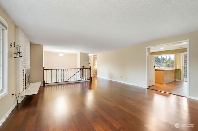 unfurnished room featuring hardwood / wood-style flooring and a brick fireplace