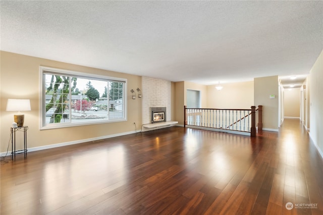 unfurnished living room with dark hardwood / wood-style flooring and a brick fireplace