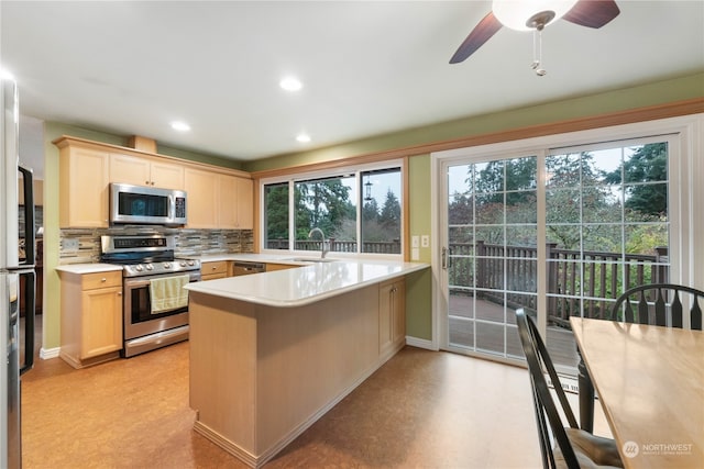 kitchen featuring kitchen peninsula, appliances with stainless steel finishes, backsplash, light brown cabinetry, and sink