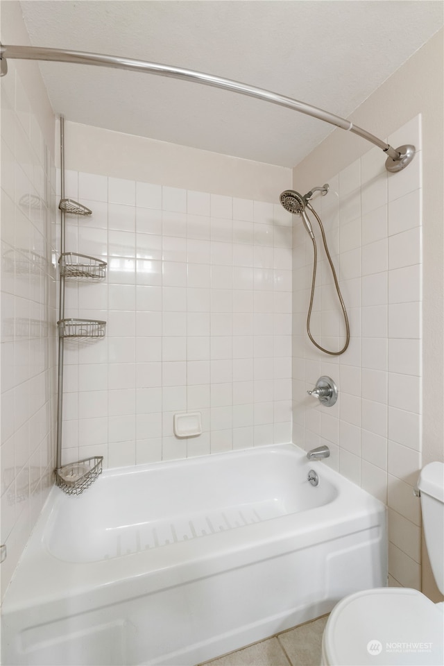 bathroom featuring tile patterned floors, tiled shower / bath combo, and toilet