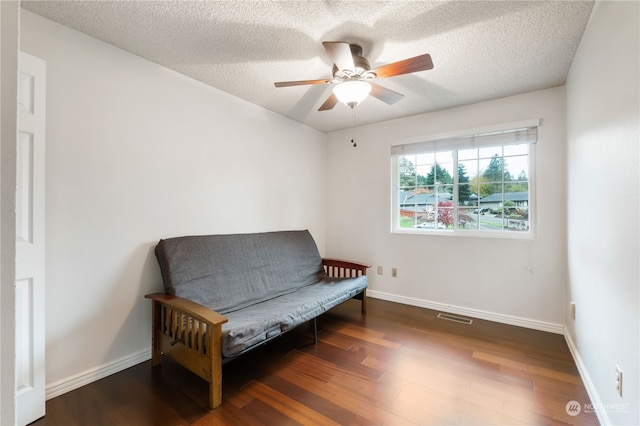 living area with a textured ceiling, dark hardwood / wood-style floors, and ceiling fan