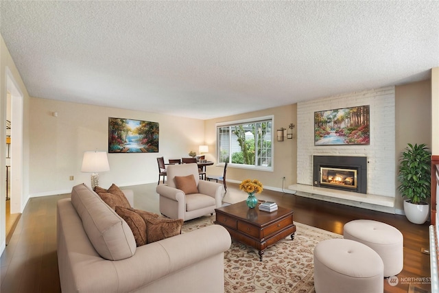 living room with a textured ceiling, wood-type flooring, and a fireplace