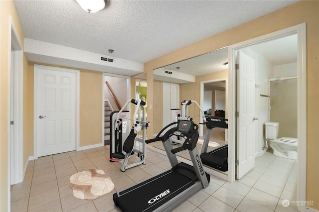 exercise room with light tile patterned floors and a textured ceiling