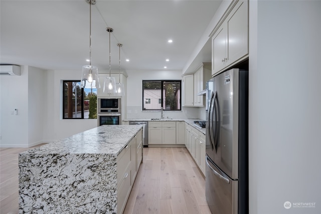 kitchen with a kitchen island, pendant lighting, a wall mounted air conditioner, white cabinets, and stainless steel appliances