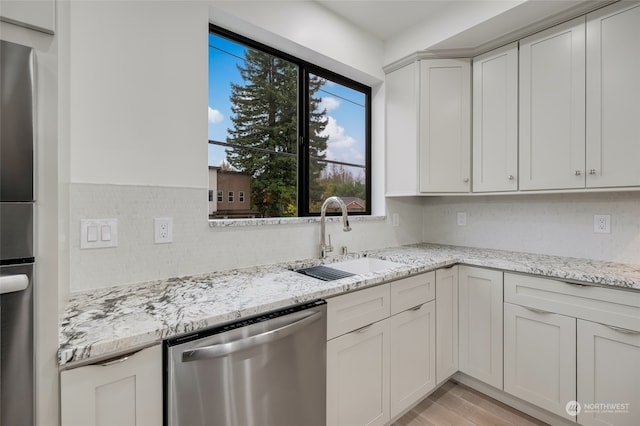 kitchen featuring stainless steel appliances, light stone countertops, sink, and white cabinets