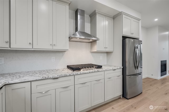 kitchen featuring white cabinetry, light hardwood / wood-style flooring, stainless steel appliances, and wall chimney exhaust hood