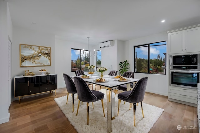 dining room featuring a wall unit AC, light hardwood / wood-style floors, and a chandelier