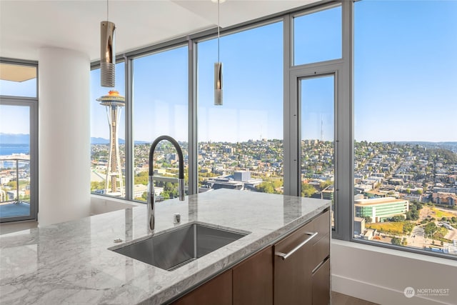 kitchen with a wealth of natural light, sink, and light stone countertops