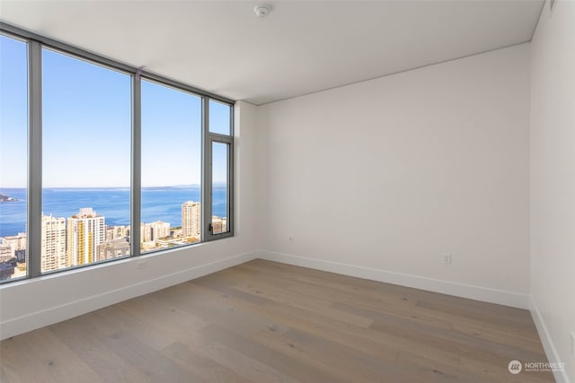 spare room with a water view and wood-type flooring