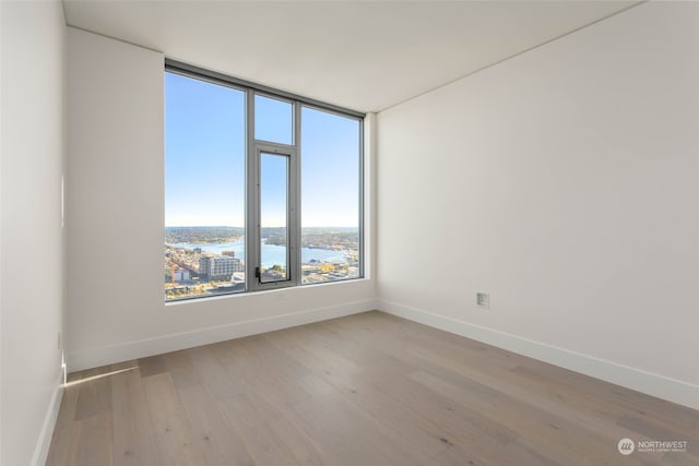 spare room with a water view and light hardwood / wood-style floors