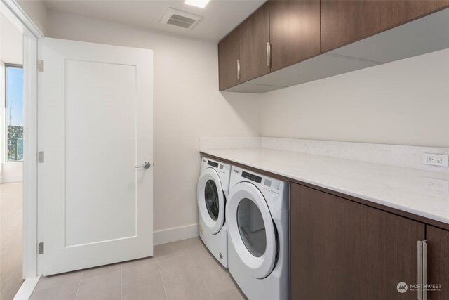 laundry area with washer and dryer, light tile patterned floors, and cabinets