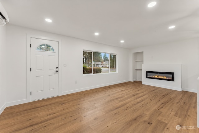 unfurnished living room with a wall mounted AC and light wood-type flooring