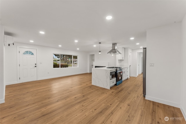 kitchen featuring white cabinets, light hardwood / wood-style flooring, exhaust hood, appliances with stainless steel finishes, and decorative light fixtures