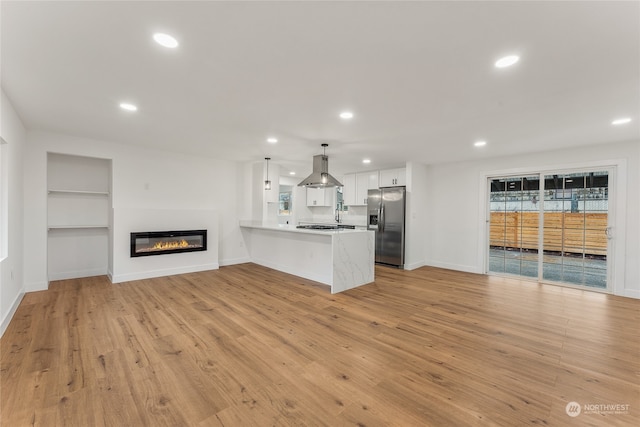 unfurnished living room featuring built in features and light hardwood / wood-style floors