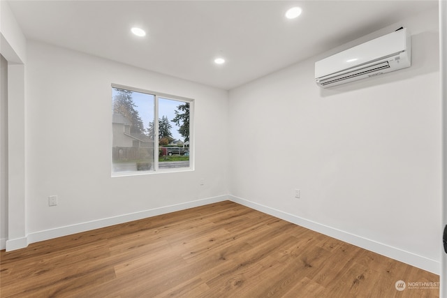 spare room featuring hardwood / wood-style floors and a wall unit AC