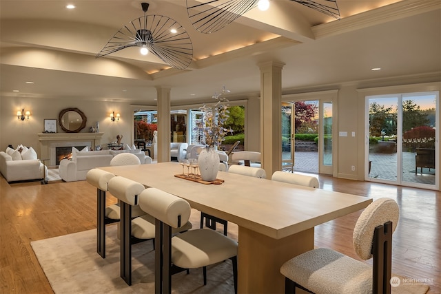 dining space with light wood-type flooring, decorative columns, and crown molding