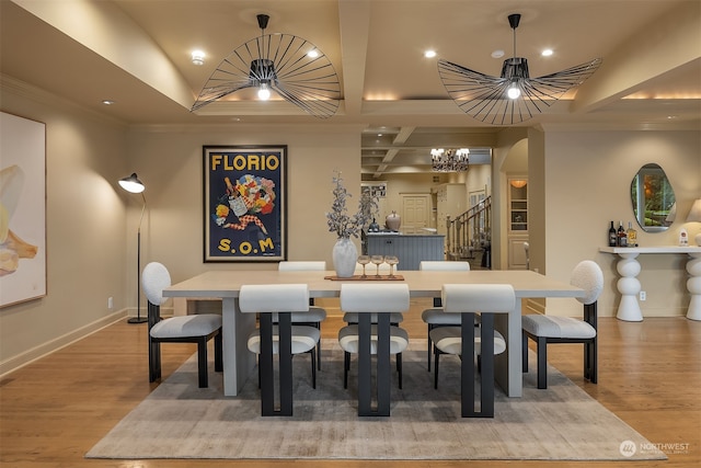 dining room featuring crown molding, a chandelier, coffered ceiling, and hardwood / wood-style flooring