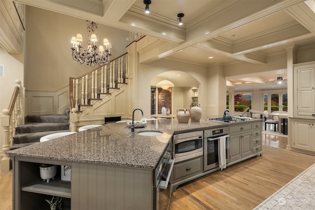 kitchen featuring gray cabinetry, sink, stainless steel appliances, light hardwood / wood-style flooring, and a center island with sink