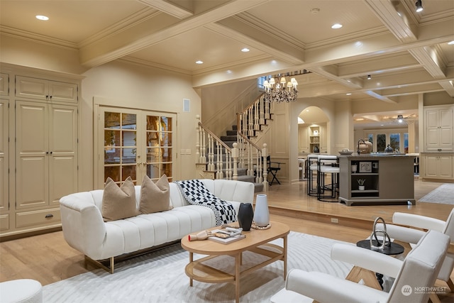 living room with coffered ceiling, crown molding, light wood-type flooring, beamed ceiling, and a chandelier