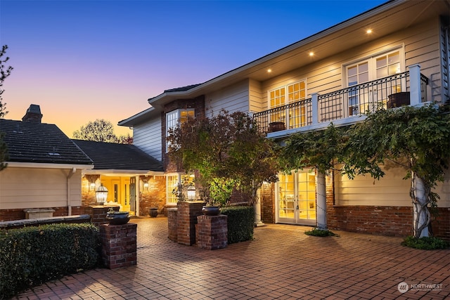 patio terrace at dusk with french doors and a balcony