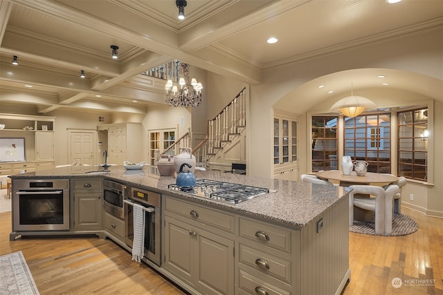 kitchen featuring stainless steel appliances, light hardwood / wood-style flooring, a center island with sink, and light stone counters