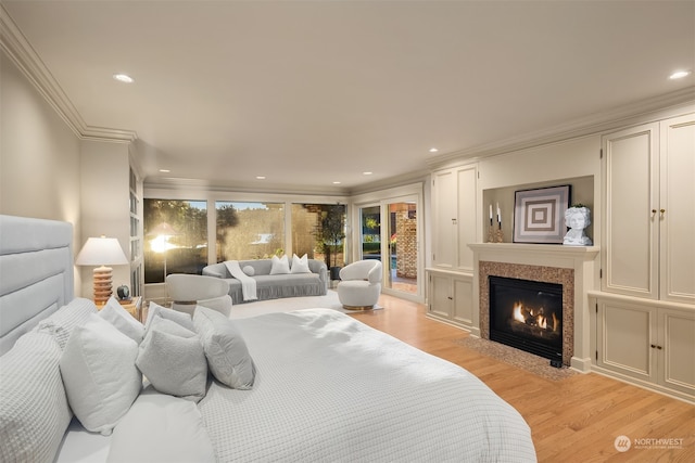 bedroom featuring light wood-type flooring, access to outside, crown molding, and a premium fireplace