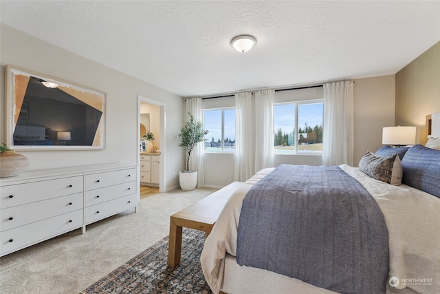 carpeted bedroom with ensuite bathroom and a textured ceiling