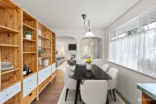 dining space featuring a textured ceiling, dark hardwood / wood-style floors, and wooden walls