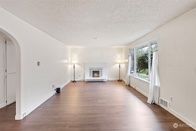 unfurnished living room with a textured ceiling and dark hardwood / wood-style floors