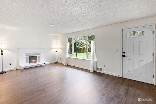 interior space featuring dark hardwood / wood-style floors, a textured ceiling, and a brick fireplace