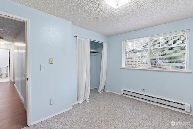 unfurnished bedroom featuring light carpet, a closet, a textured ceiling, and a baseboard heating unit