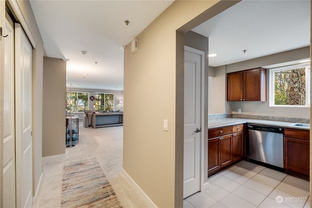 kitchen with plenty of natural light, stainless steel dishwasher, and light colored carpet