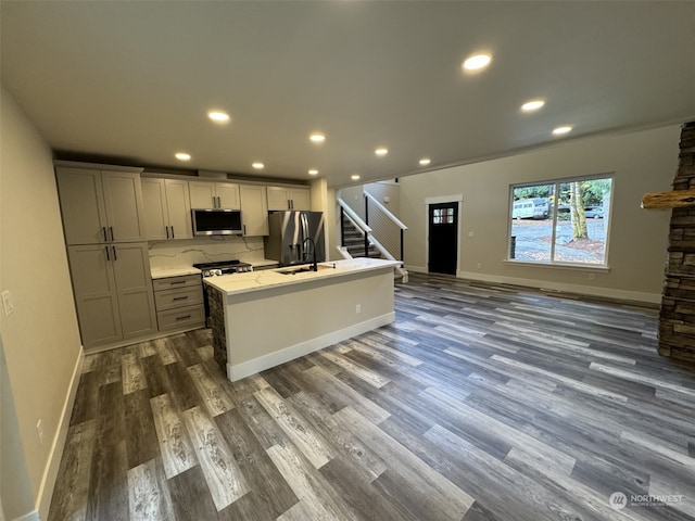 kitchen with gray cabinets, dark wood-type flooring, an island with sink, and stainless steel appliances