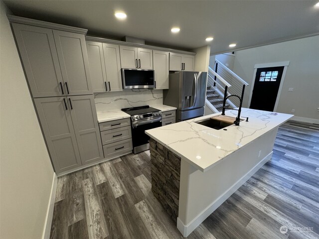 111 Heather Pl, Packwood, WA 98361 - kitchen with stainless steel appliances, a sink, dark wood-style floors, an island with sink, and baseboards