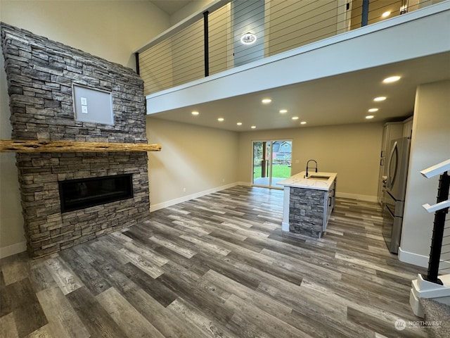 unfurnished living room featuring sink, a fireplace, a high ceiling, and dark hardwood / wood-style floors