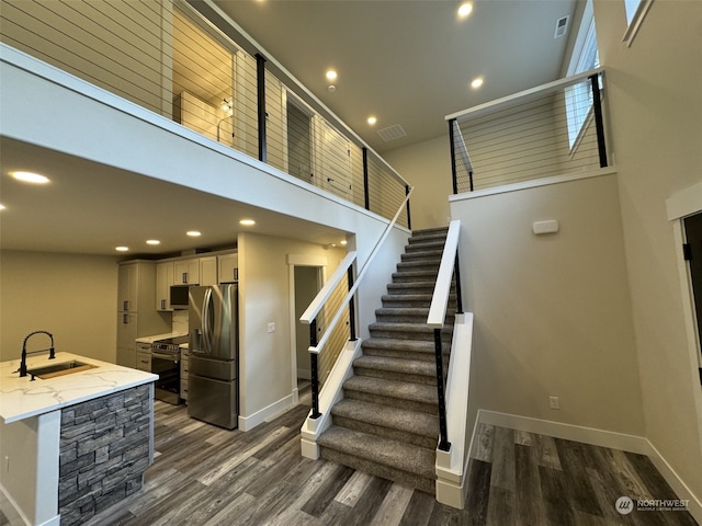 stairway featuring sink, wood-type flooring, and a high ceiling