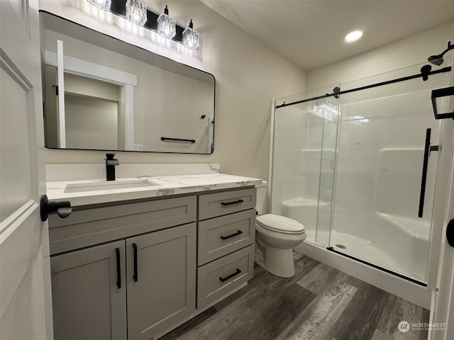 bathroom with a shower with door, vanity, hardwood / wood-style flooring, and toilet