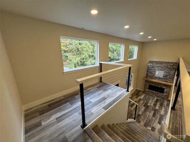 staircase with a stone fireplace and hardwood / wood-style flooring