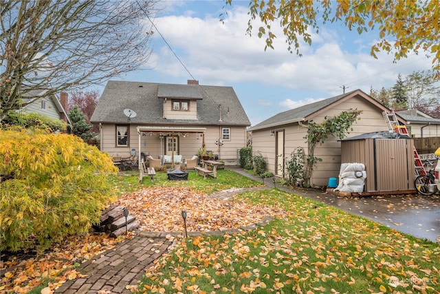 back of property featuring an outdoor structure and an outdoor fire pit