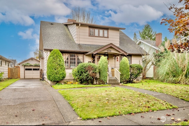 bungalow with a garage, an outdoor structure, and a front lawn