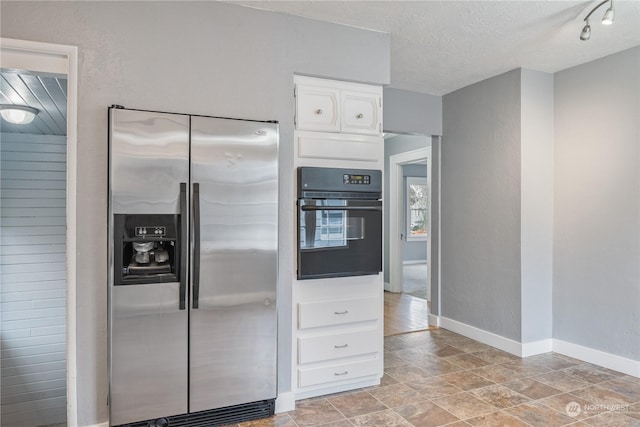 kitchen featuring white cabinets, stainless steel fridge with ice dispenser, a textured ceiling, and oven