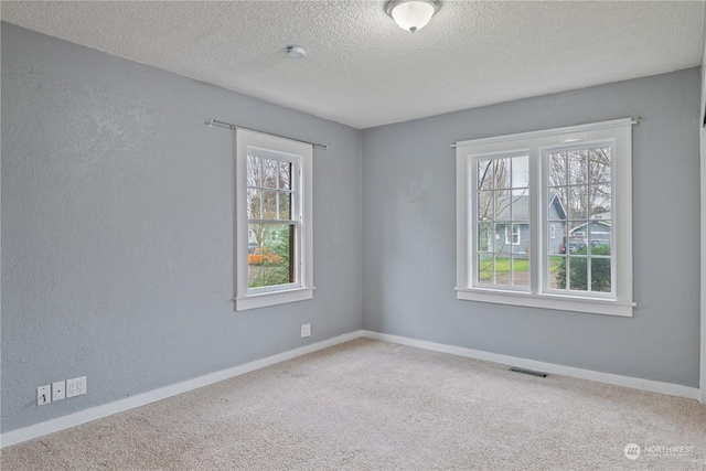 spare room with a textured ceiling and carpet floors