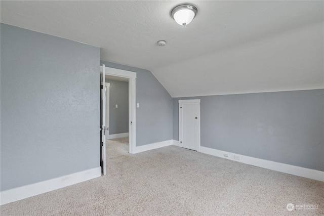 bonus room with light colored carpet and lofted ceiling