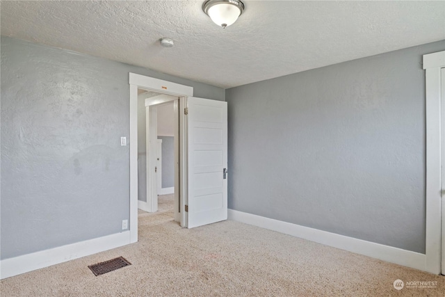 carpeted spare room with a textured ceiling