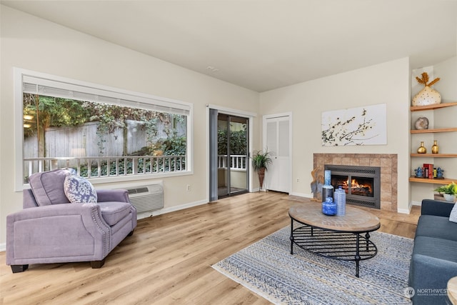 living room featuring a fireplace, hardwood / wood-style flooring, and a wall mounted air conditioner