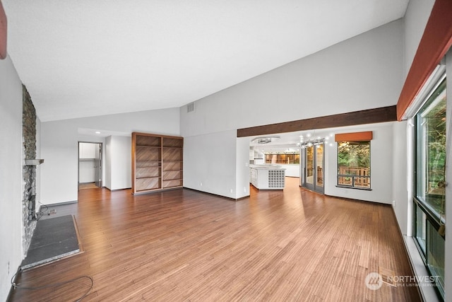 unfurnished living room with hardwood / wood-style floors, high vaulted ceiling, and a healthy amount of sunlight