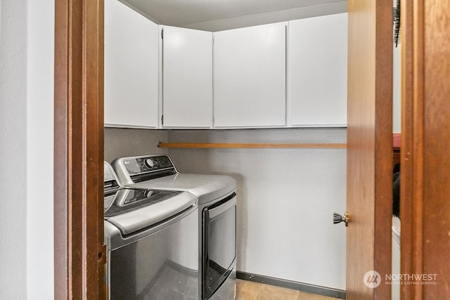 laundry area featuring washing machine and dryer, light tile patterned flooring, and cabinets